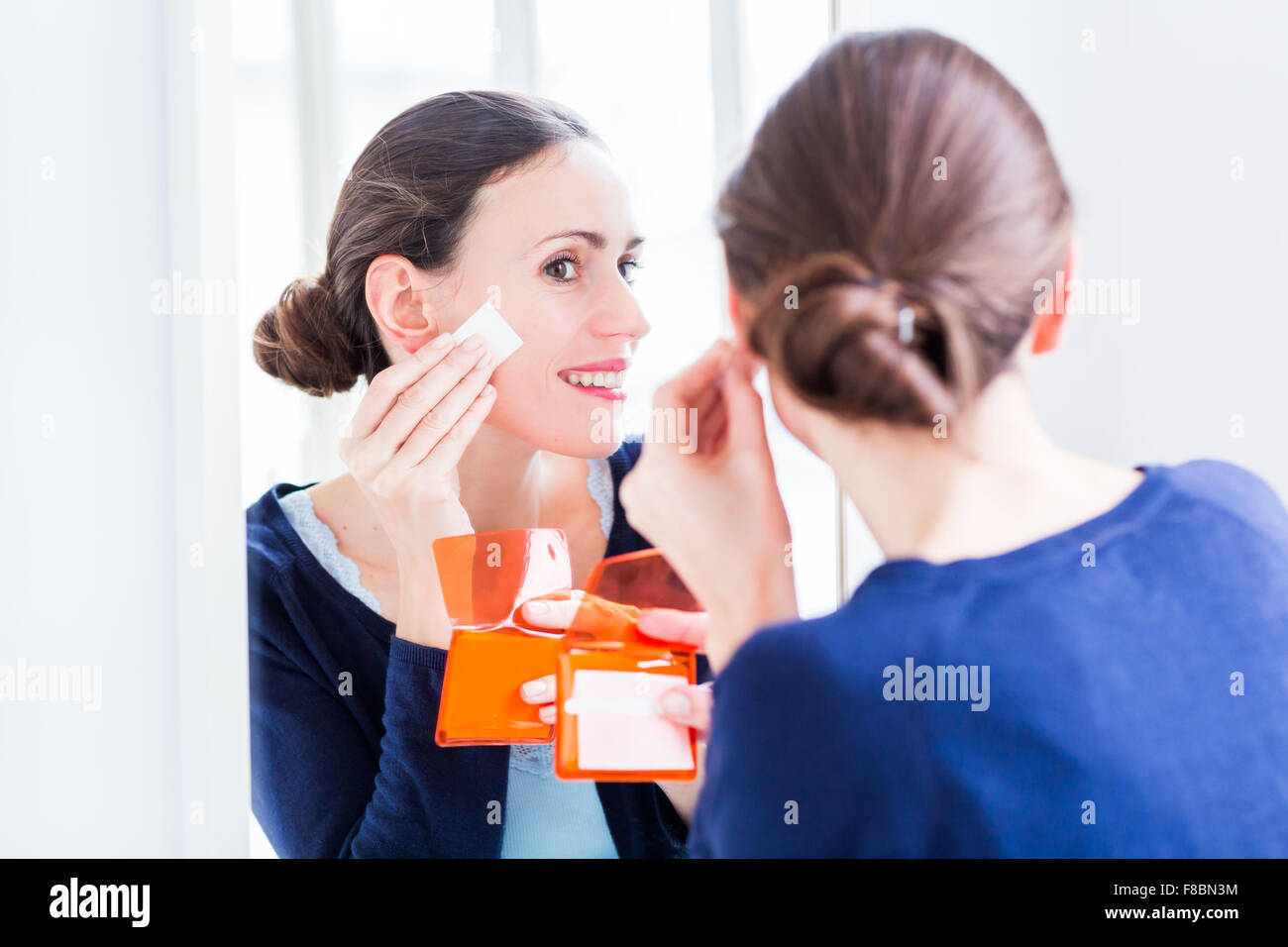 Donna che utilizza la carta assorbente contro la pelle che si illumina . Foto Stock
