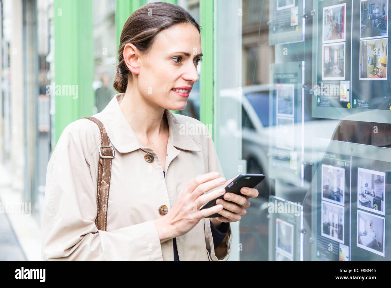 Donna che guarda per gli annunci in una agenzia immobiliare. Foto Stock
