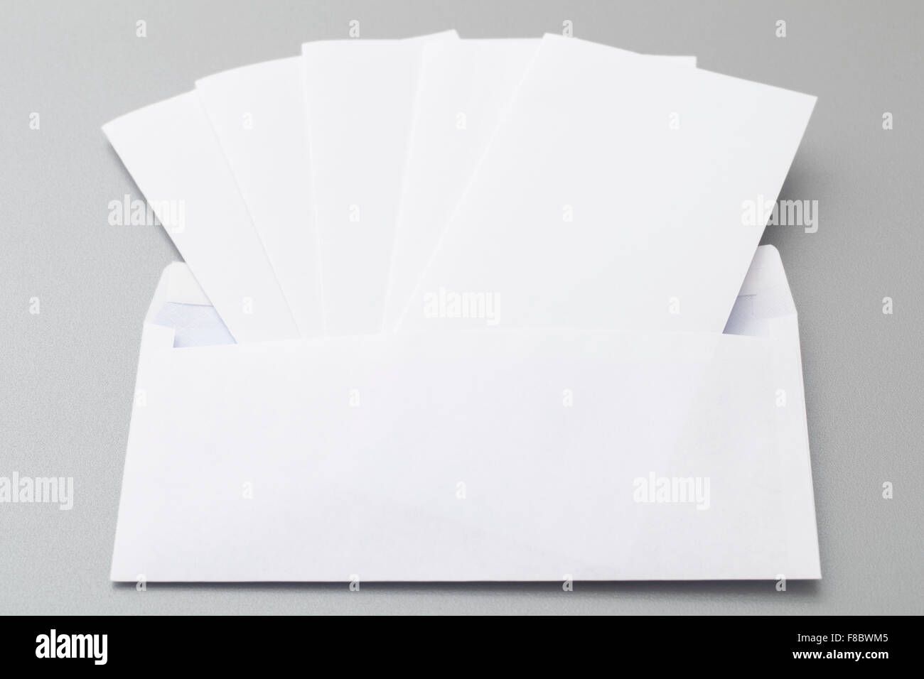 Cinque piegati i fogli bianchi mettere in vuoto busta bianca, isolato su sfondo. Foto Stock