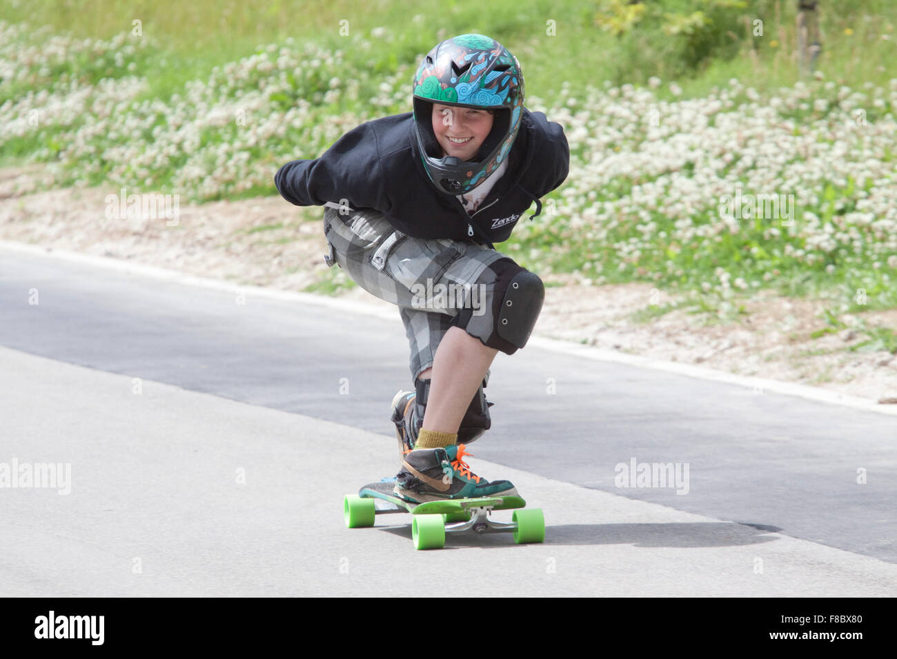 Ragazzo adolescente su skateboard sorrisi felicemente con la videocamera Foto Stock