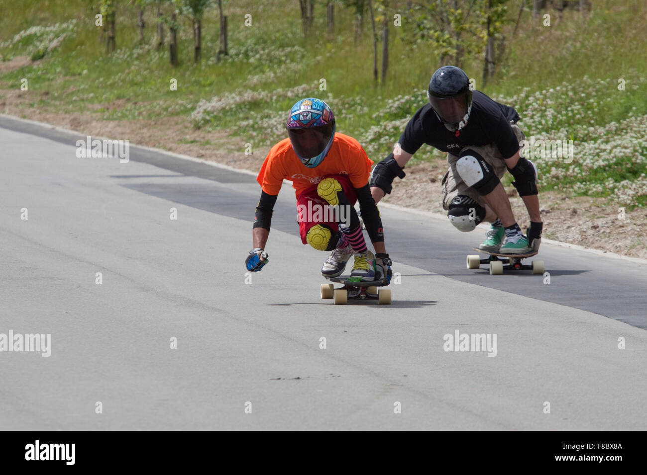 Due down hill skateboarders in nero pieno viso visiere guardare piuttosto misterioso Foto Stock