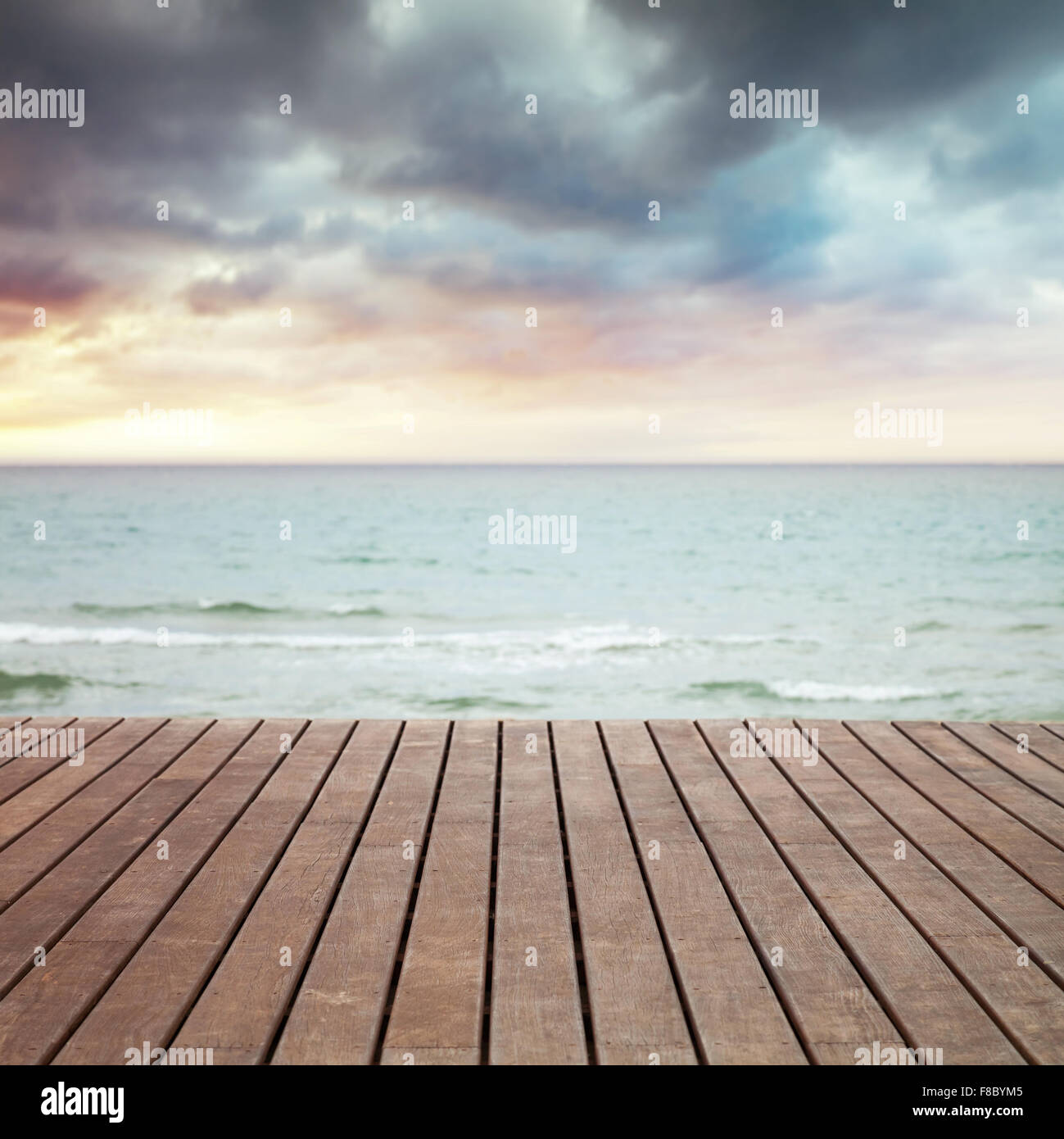 Il mare, la sabbia e il molo in legno prospettiva, foto quadrata con messa a fuoco selettiva e sfocata sullo sfondo del cielo Foto Stock