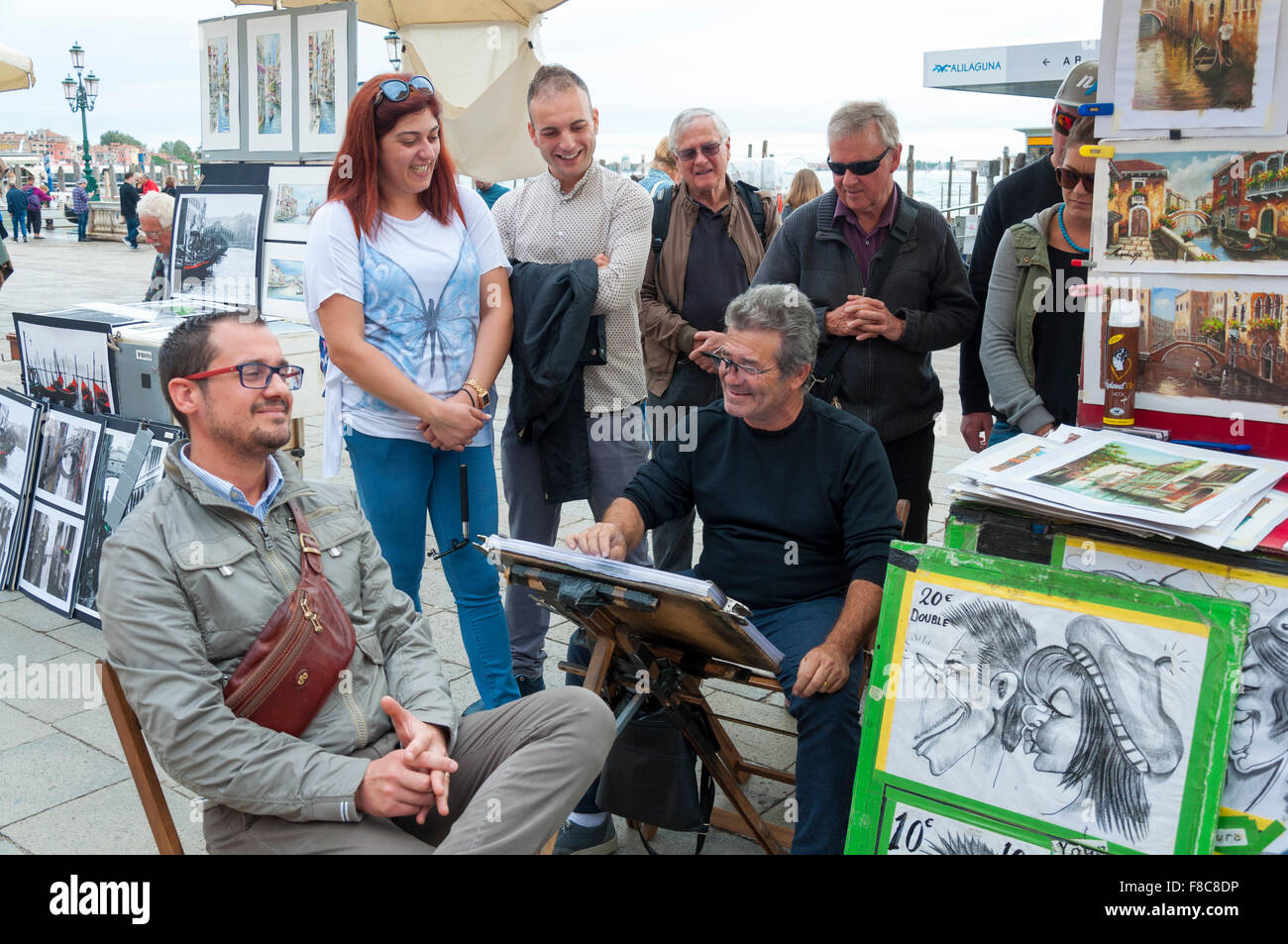 Un turista ha una caricatura Bozzetto disegnato da un artista a Venezia, Italia Foto Stock