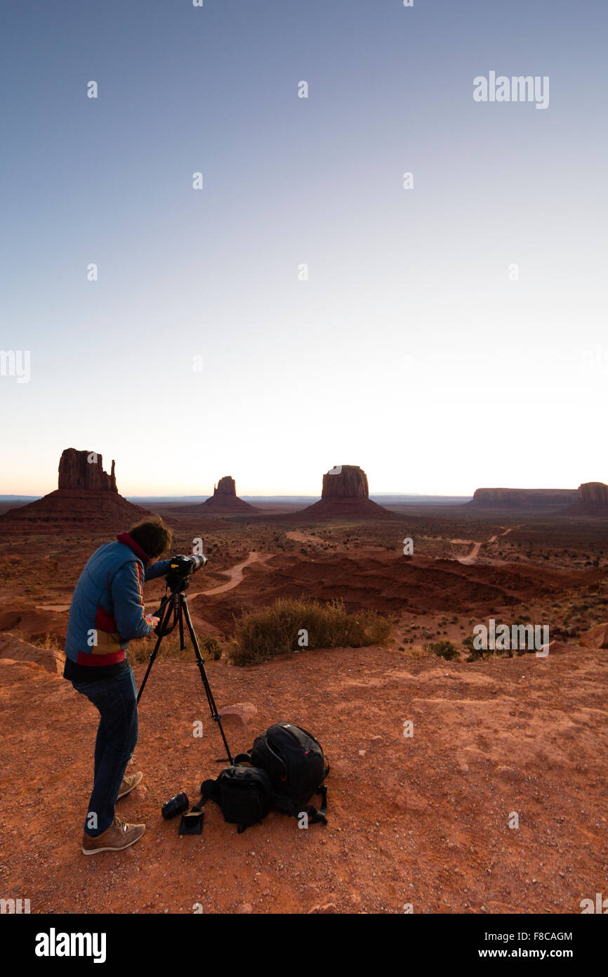 Il Monument Valley, Arizona. Un fotografo con il suo equipaggiamento di prendere una fotografia della vista a valle monumento all'alba. Foto Stock
