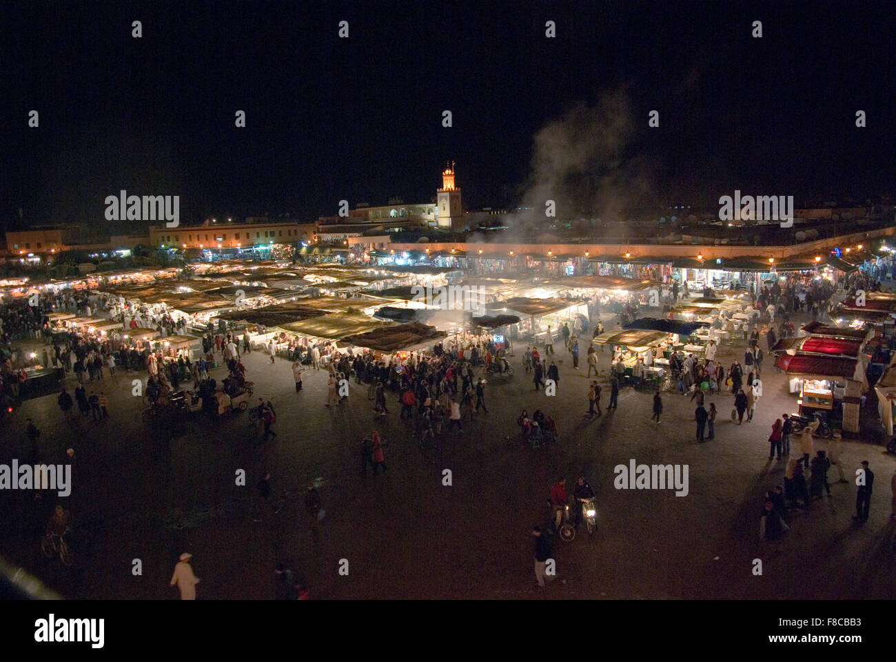 Piazza principale Piazza Jemaa El Fnaa di Marrakech di notte pranzo con stand gastronomici, fumo oltre le luci, la moschea in background Foto Stock