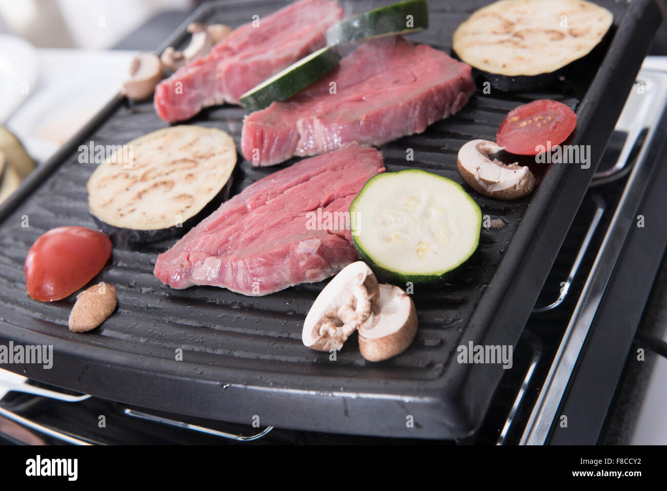 Bistecche e funghi sulla raclette per la cottura Foto Stock