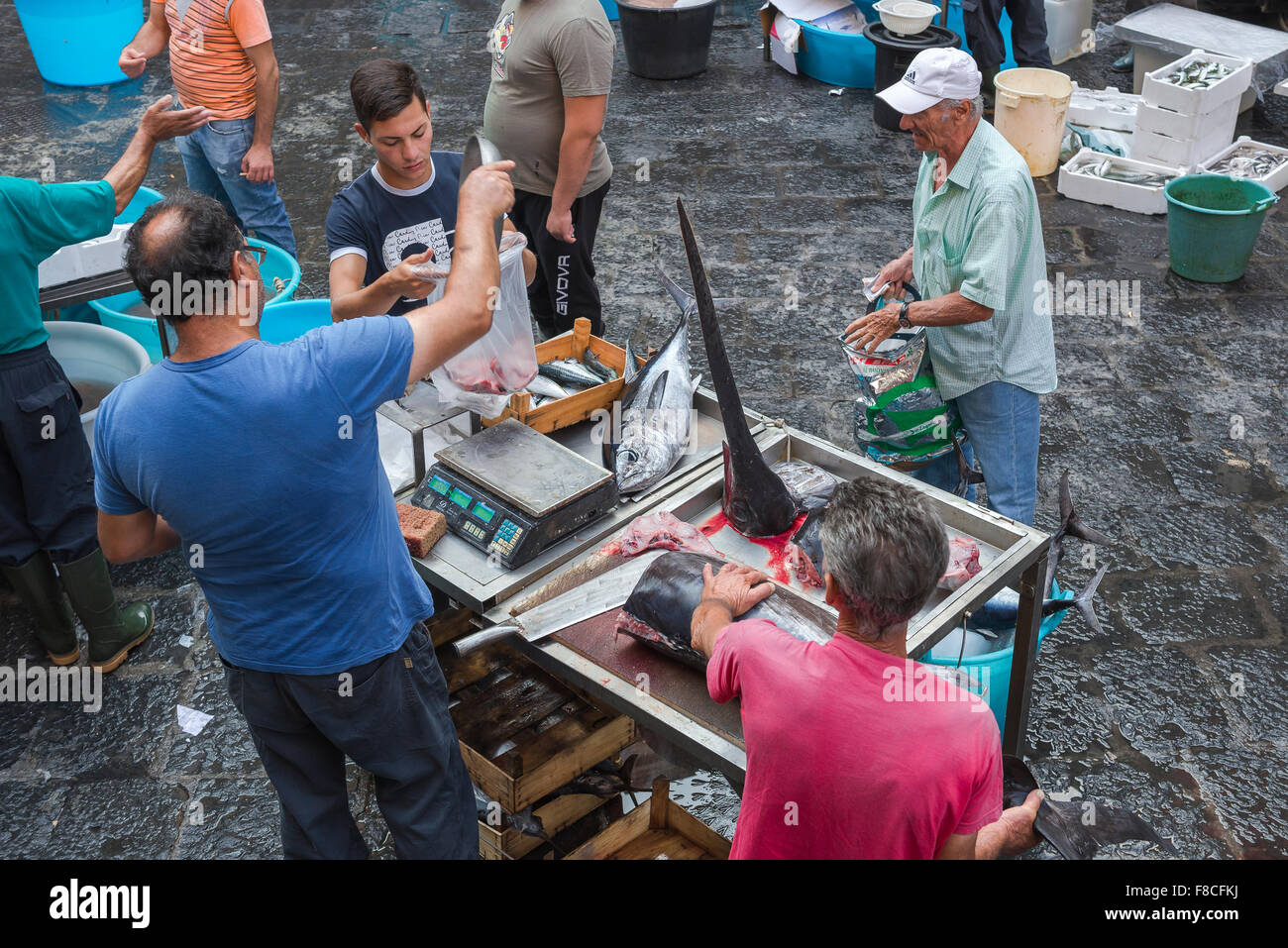 Catania mercato del pesce, la vista di un uomo l'acquisto di pesce spada in una trafficata mattina a Catania il famoso mercato del pesce (Mercato della Pescheria), Sicilia. Foto Stock