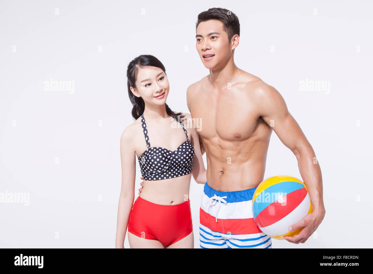 Matura in spiaggia indossare insieme con le loro braccia intorno a ogni altro uomo e tenendo una palla spiaggia Foto Stock