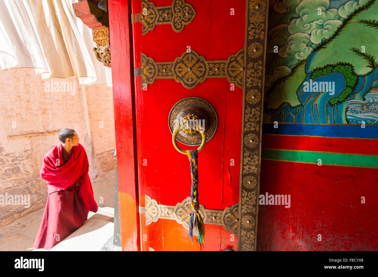 Giovane monaco nella parte anteriore del porta rossa tempio Foto Stock