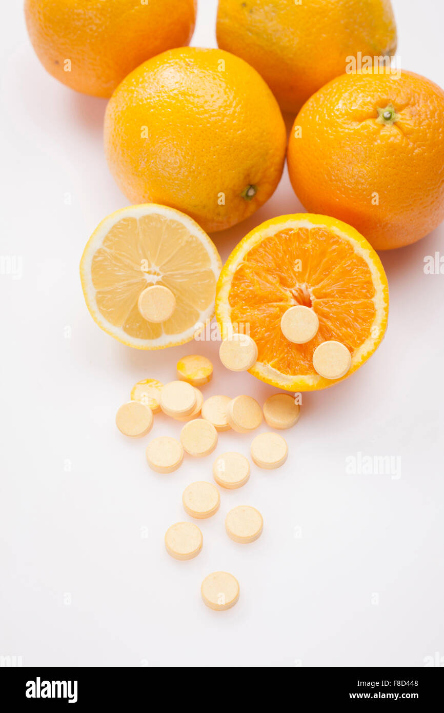 Elevato angolo di una fettina di limone e una fetta di arancia con arance fresche e di colore giallo della vitamina pillole Foto Stock