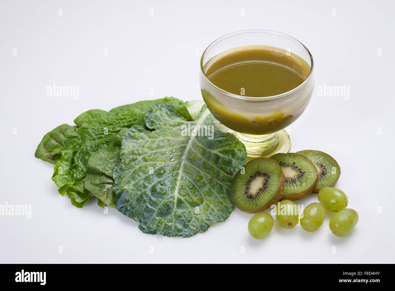 Bicchiere di succo verde con verdure e frutti verdi compresi kiwi e uva Foto Stock