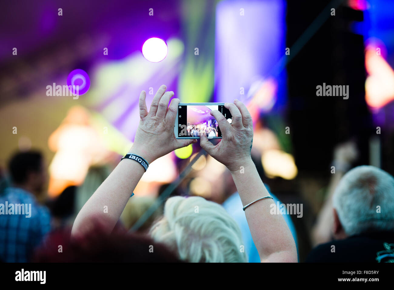 Vista posteriore di una persona utilizzando il proprio telefono cellulare per registrare la banda di pagare al grande tributo Music Festival, Aberystwyth, Agosto weekend festivo, Estate 2015 Foto Stock