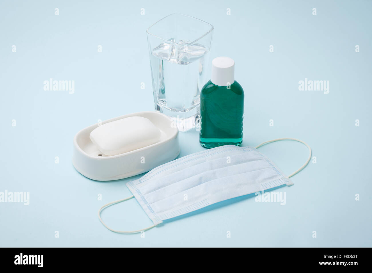 Bottiglia di collutorio, un bicchiere di acqua e un sapone e una maschera Foto Stock