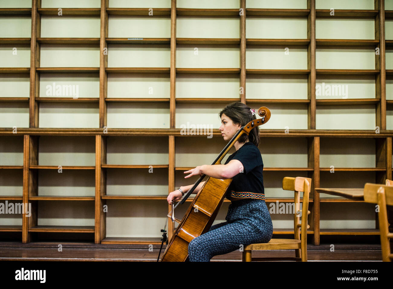 Giovani musicisti classici: la violoncellista della Solem String Quartet giocando da solo sul suo violoncello in una libreria vuota a Aberystwyth Music Fest 2015 Foto Stock