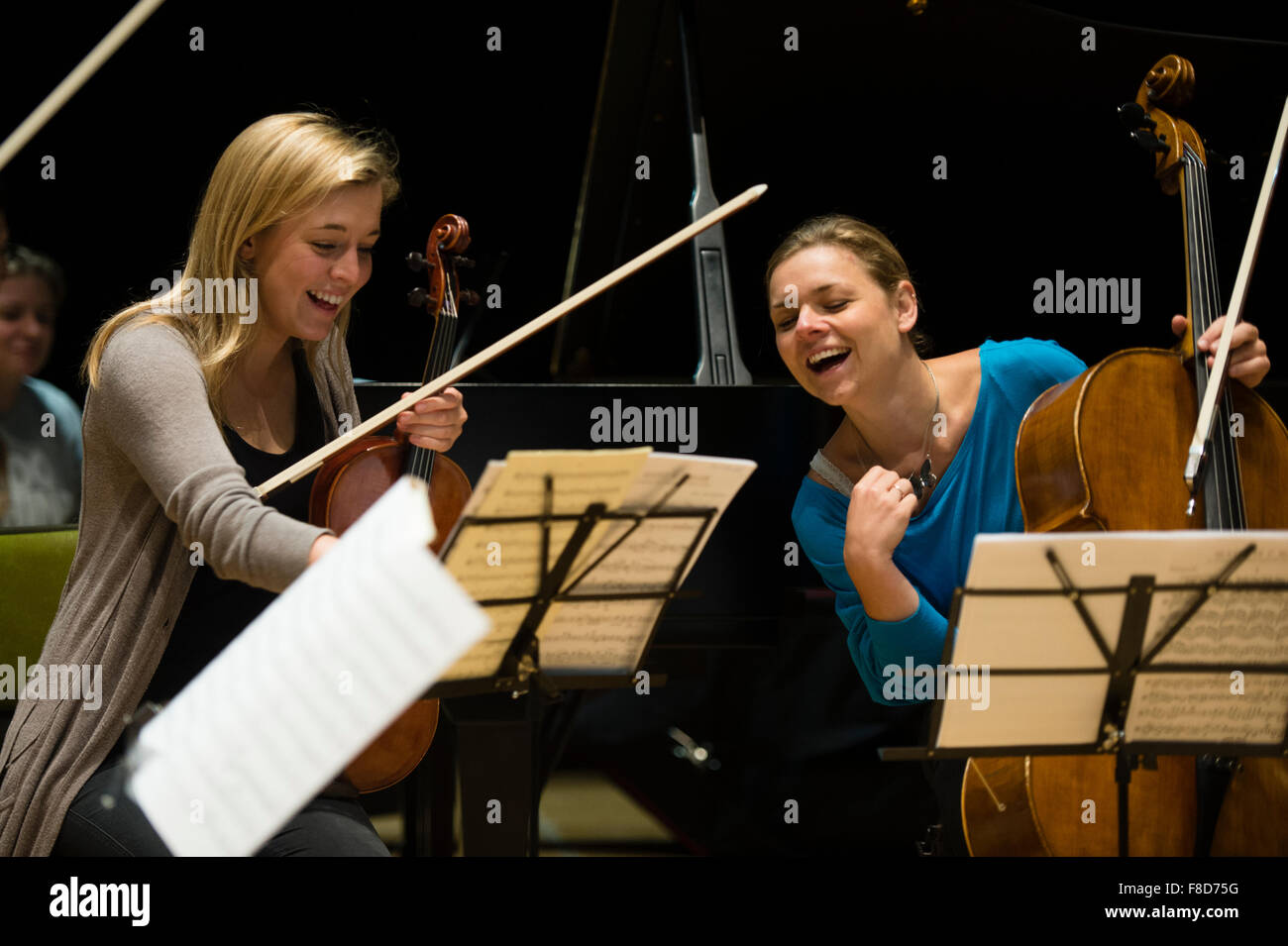 Giovani musicisti: due felici donne che ridono di musica classica (violino Ruth Nelson) e violoncello giocatori (Auriol Evans) in prove in Aber Music Fest Festival 2015 Foto Stock