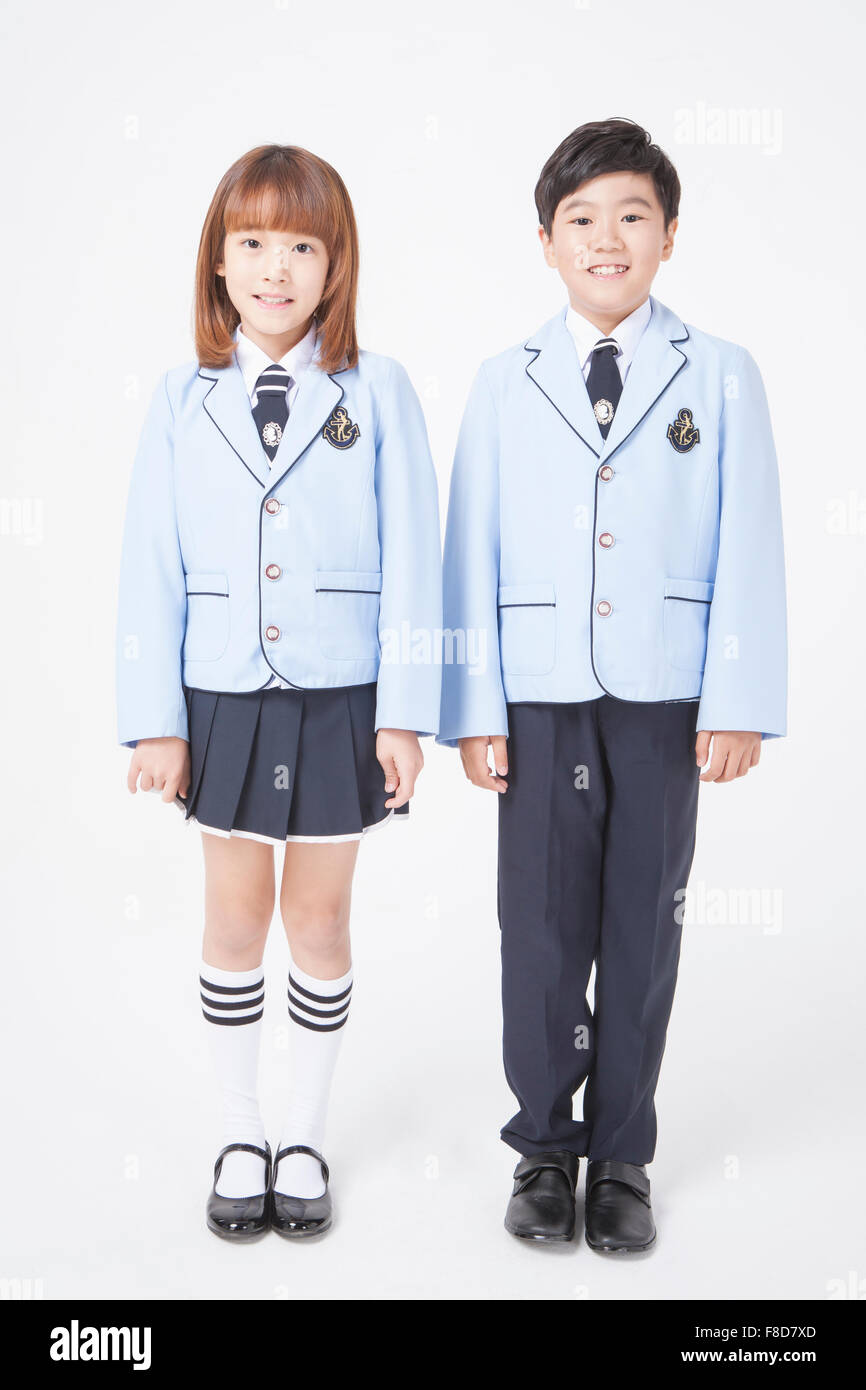 Scuola elementare età ragazza e ragazzo in uniformi di scuola in piedi accanto a ciascun altro Foto Stock
