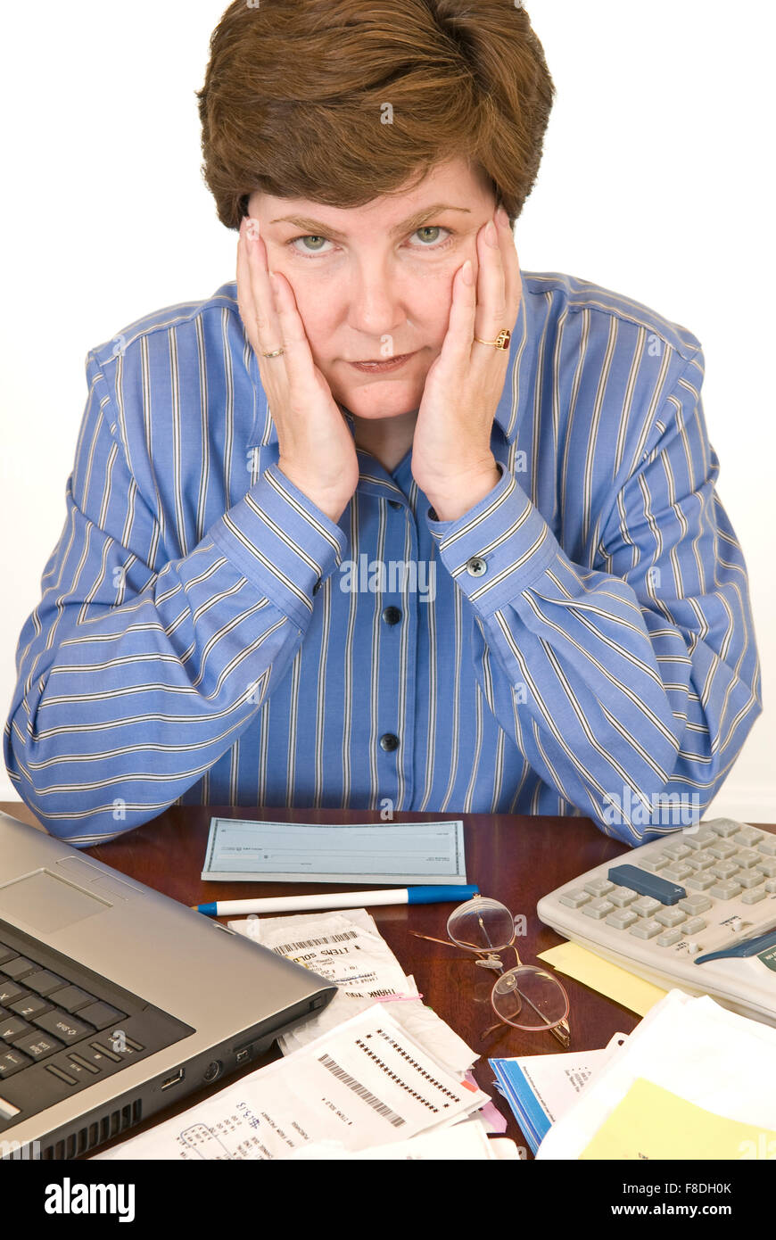 Una donna di mezza età che circondano il suo laptop, assegni, Calcolatrice e documenti cercando finanziariamente sopraffatti. Foto Stock