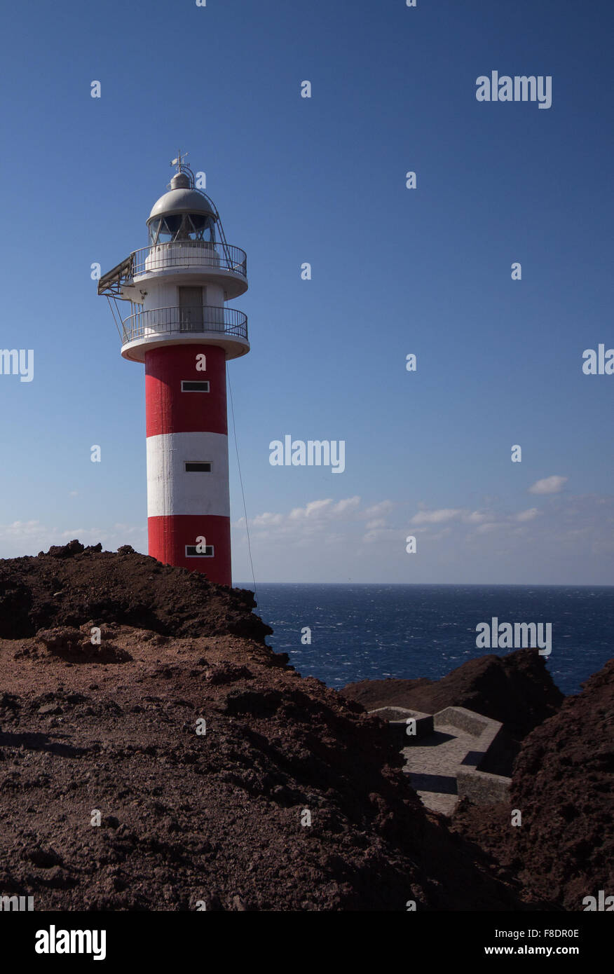 Rosso, bianco faro con sfondo oceano su roccia Foto Stock