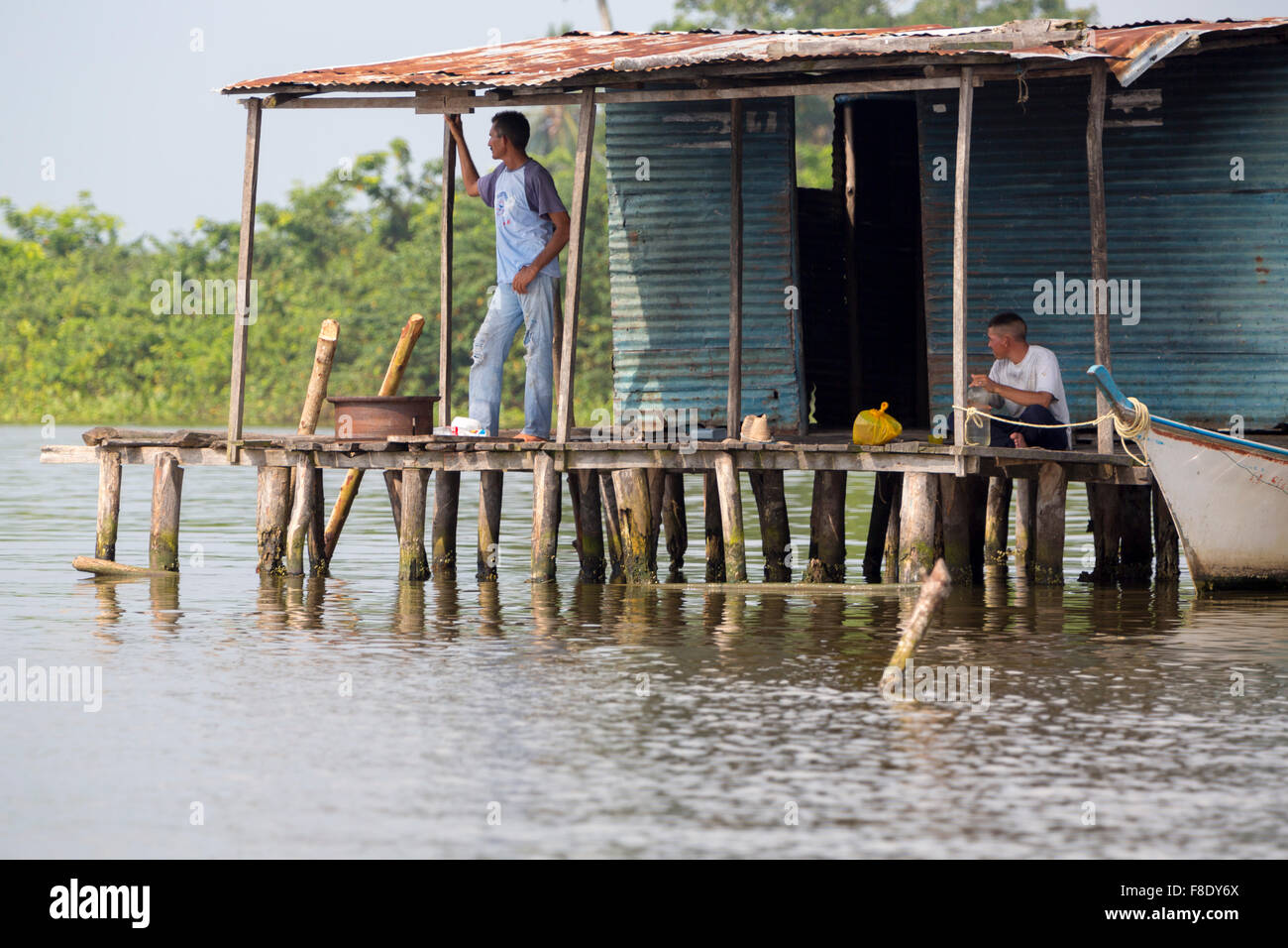 Fisher uomini seduti nelle povere case di legno sollevata sul lago di Maracaibo, Venezuela Foto Stock