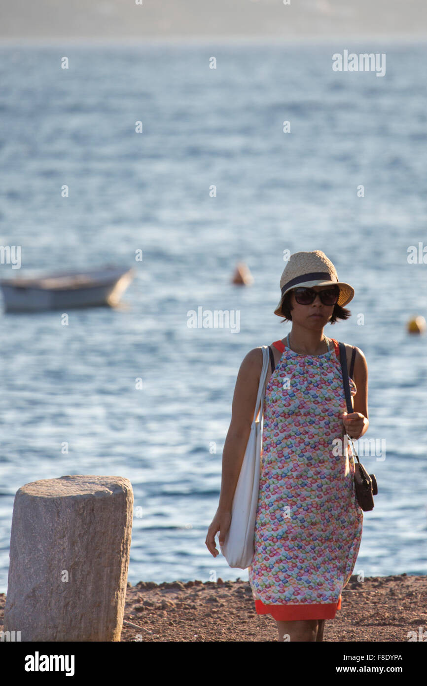 Donna cinese tourist camminando su una spiaggia con la fotocamera Foto Stock