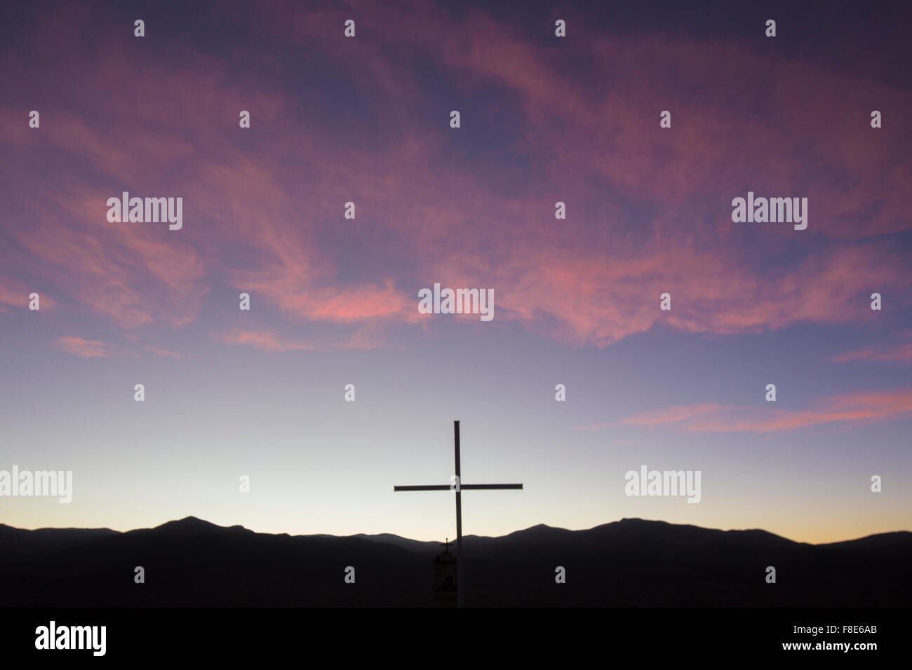 Colorato tramonto viola con la silhouette di una croce cristiana si trova in cima a una montagna a 4500m. Altiplanos, Bolivia. Foto Stock