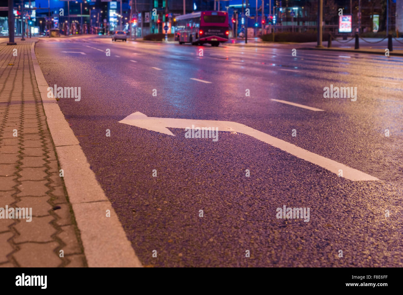 Girare a sinistra firmare la marcatura su asfalto, notte il traffico della città sullo sfondo Foto Stock