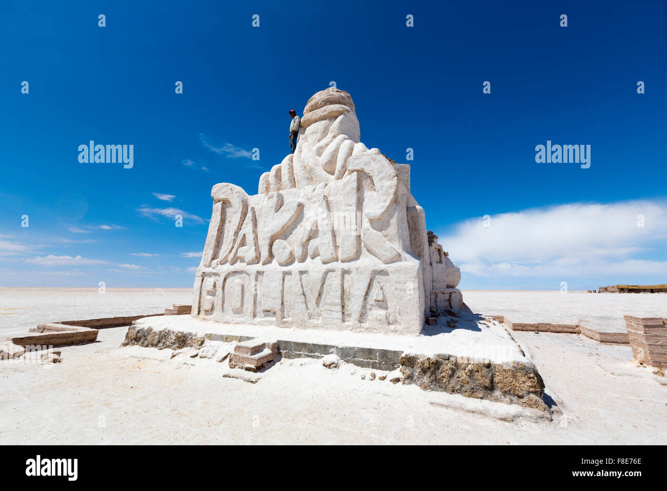 Giovane uomo in piedi sulla parte superiore della Parigi Dakar enorme scultura di sale di Uyuni. Questo monumento è dedicato Foto Stock