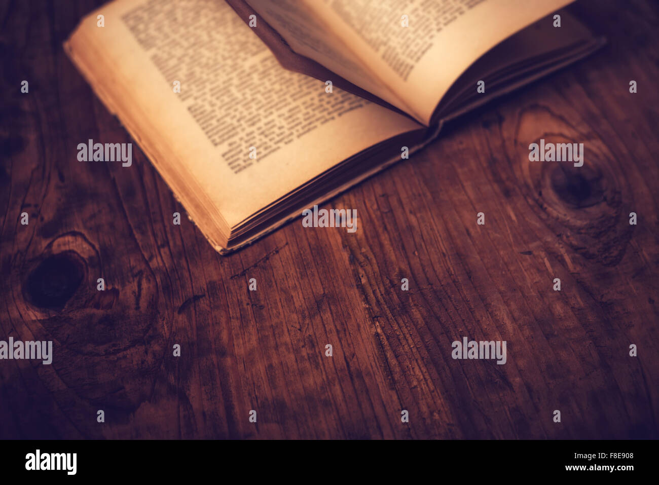 Vecchio libro libreria in legno scrivania con testo illeggibile, dai toni rétro immagine, il fuoco selettivo Foto Stock