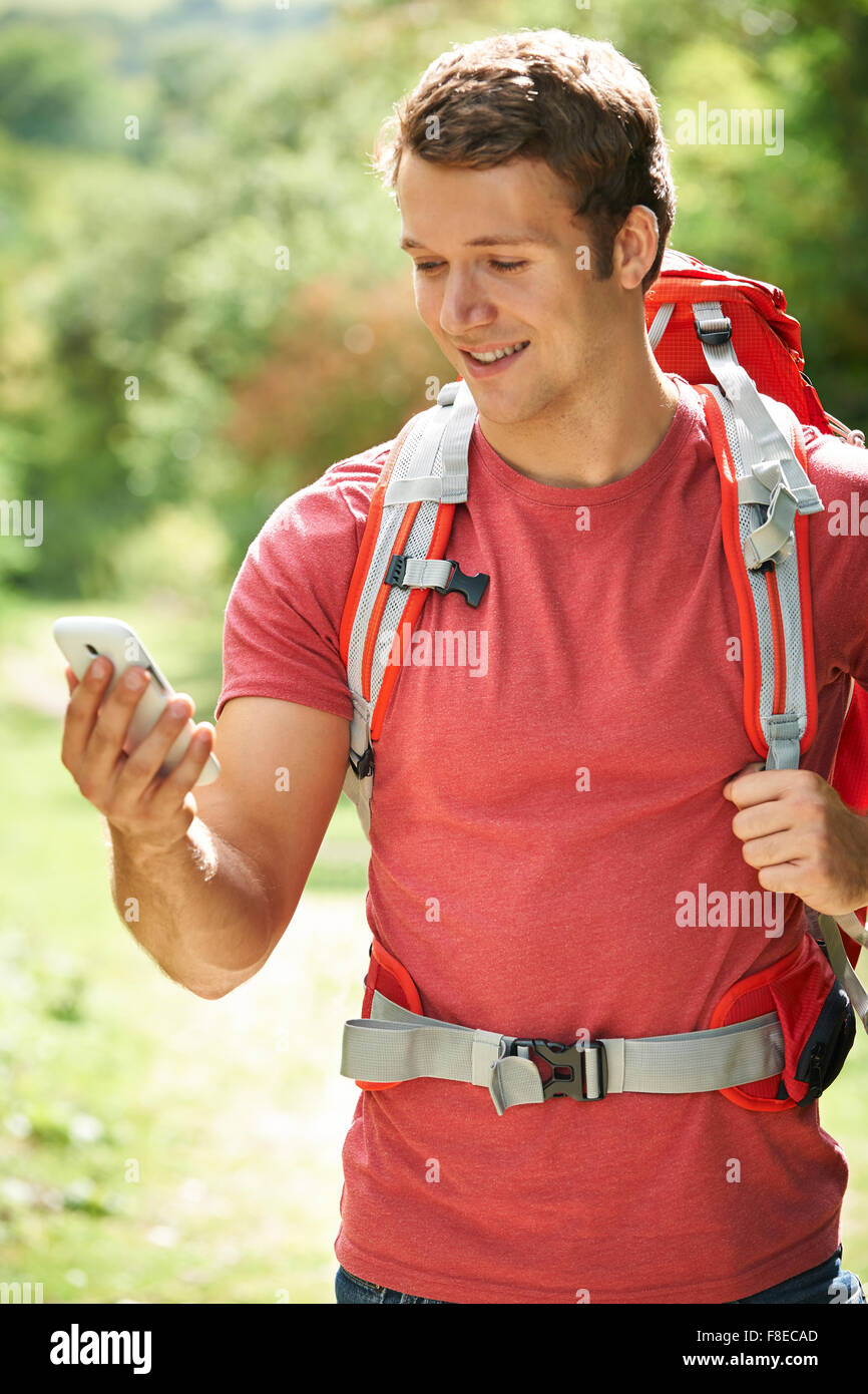 L'uomo posizione di controllo con il cellulare su escursione Foto Stock