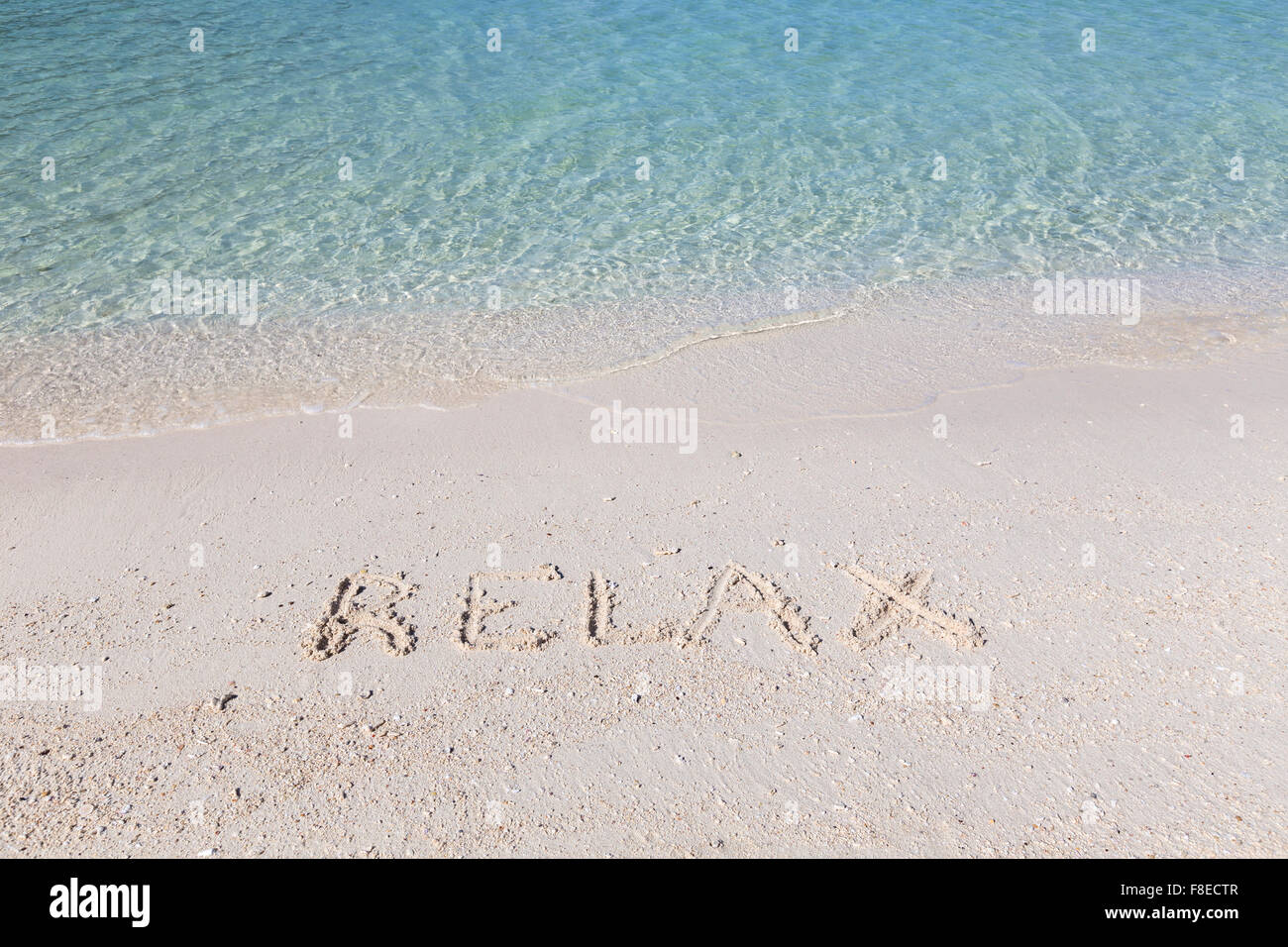 Rilassatevi scritta in sabbia bagnata su una spiaggia tropicale in Tailandia Foto Stock