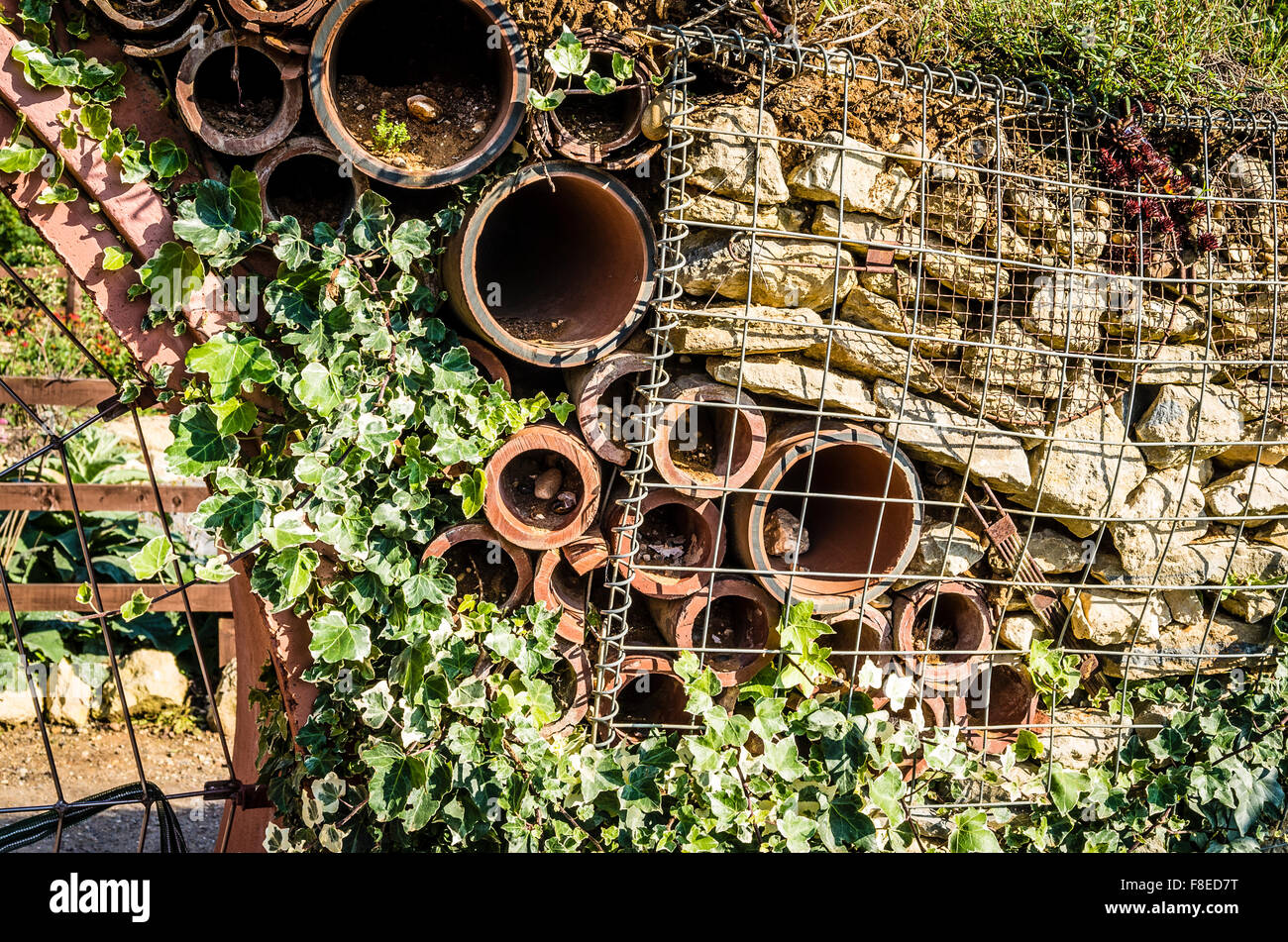 Domestico riciclato e costruzione di rifiuti riciclati in uso come una parete di contenimento in un giardino con alloggiamenti fornendo case per insetti e fauna selvatica Foto Stock