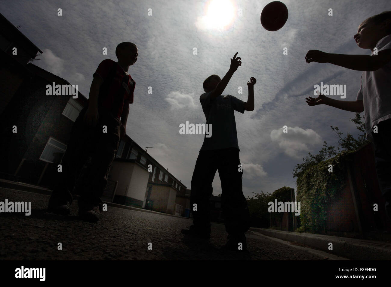 Silhouette di bambini che giocano con una palla per le strade in Oldham , REGNO UNITO Foto Stock
