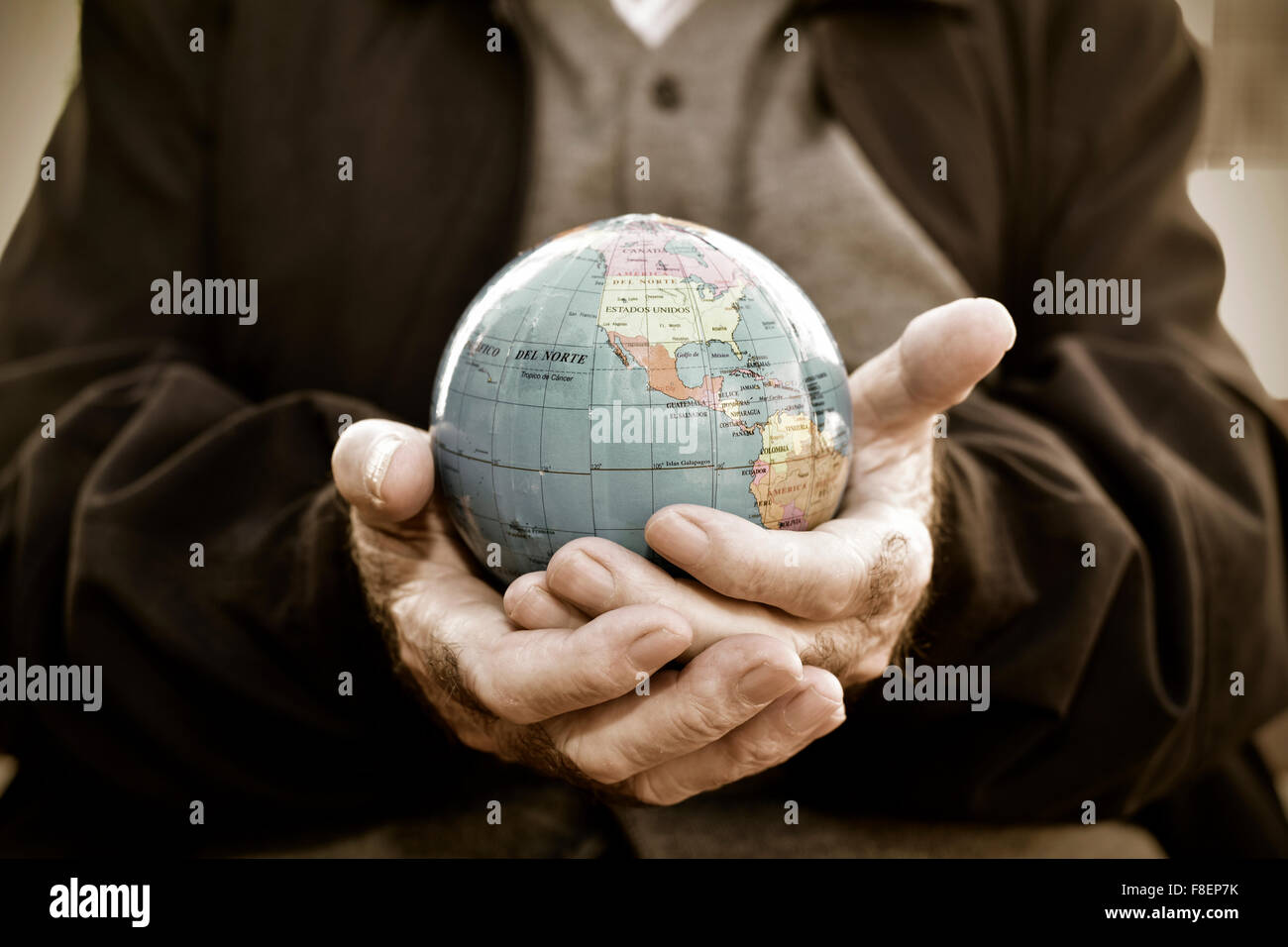 Primo piano di un vecchio uomo caucasico con un globo mondo nelle sue mani e con un effetto drammatico Foto Stock