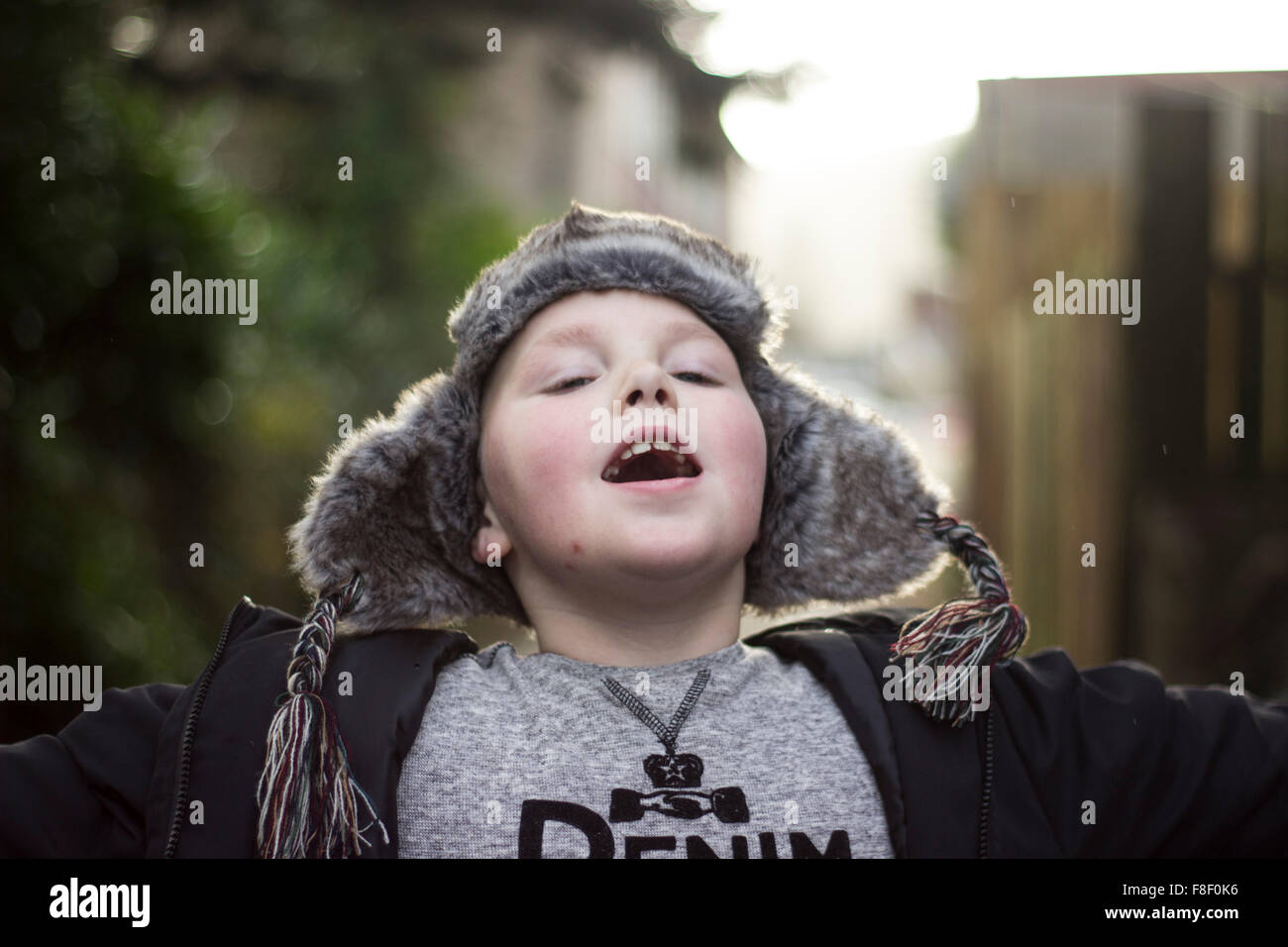 Giovane ragazzo giocando felicemente all'aperto, indossando abiti invernali. Foto Stock