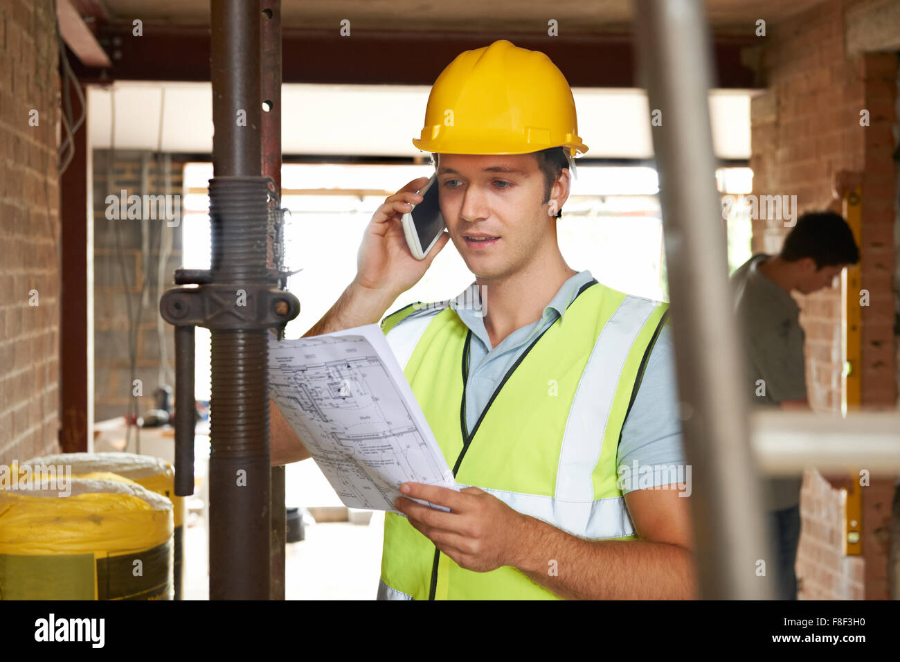 Builder sul sito usando il telefono cellulare Foto Stock