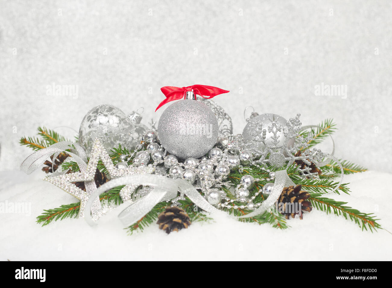 Bellissime decorazioni di Natale e rami di abete sulla neve su argento sfondo bokeh di fondo Foto Stock