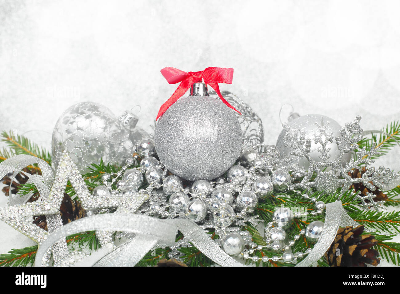 Bellissime decorazioni di Natale e rami di abete sulla neve su argento sfondo bokeh di fondo Foto Stock