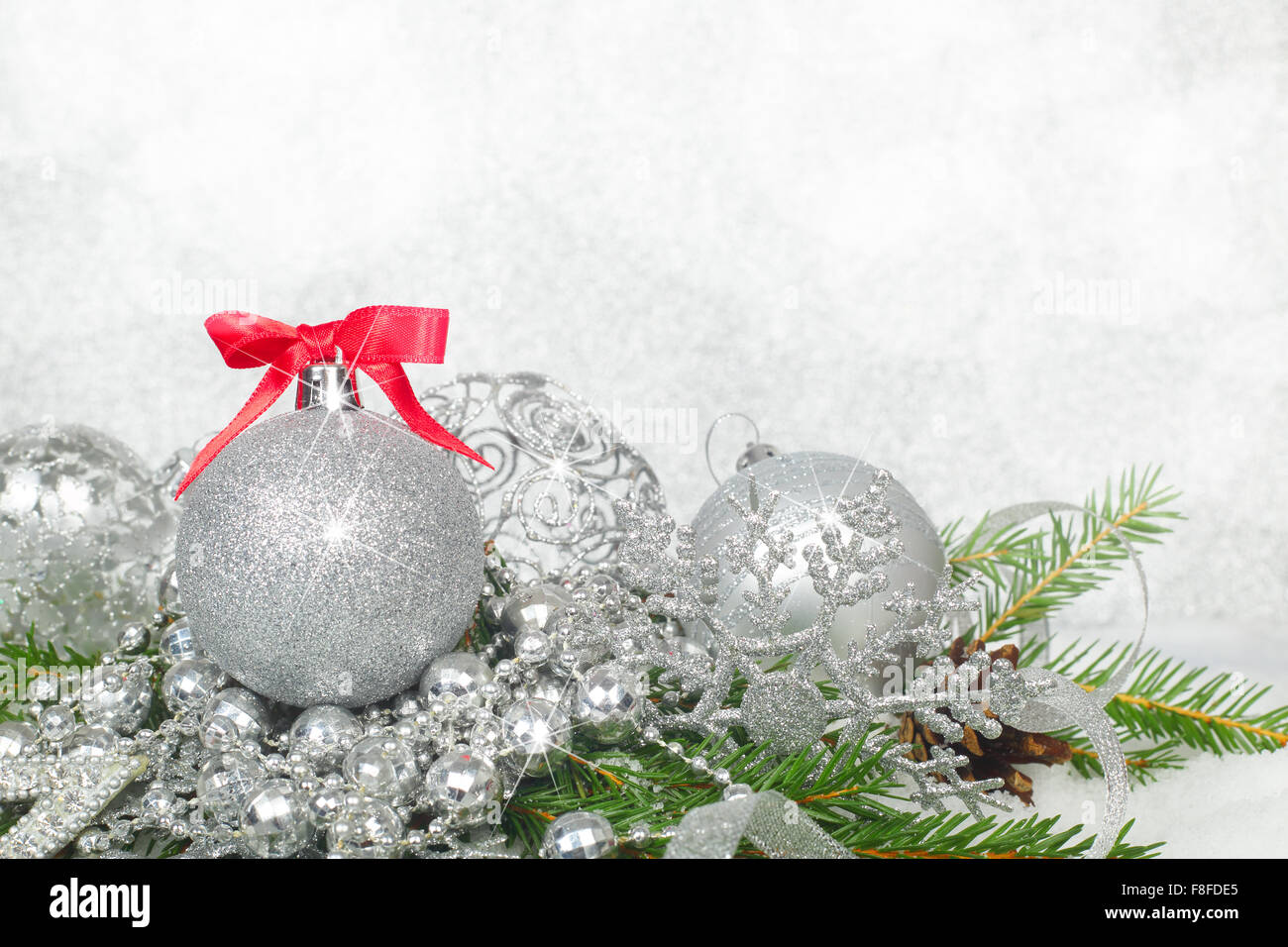 Bellissime decorazioni di Natale e rami di abete sulla neve su argento sfondo bokeh di fondo Foto Stock
