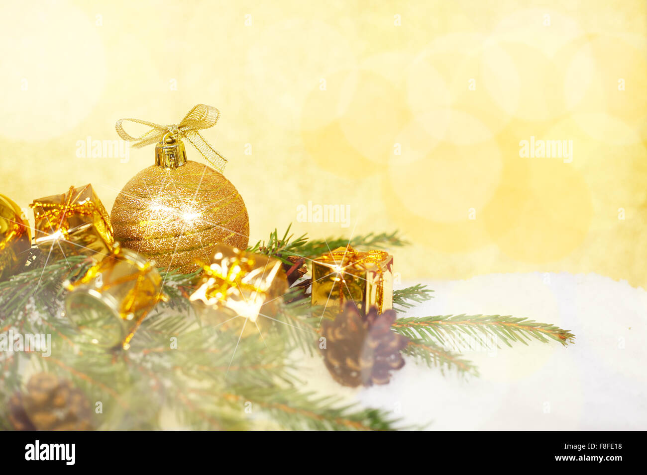 Bellissime decorazioni di Natale e rami di abete sulla neve oltre il golden sfondo bokeh di fondo Foto Stock