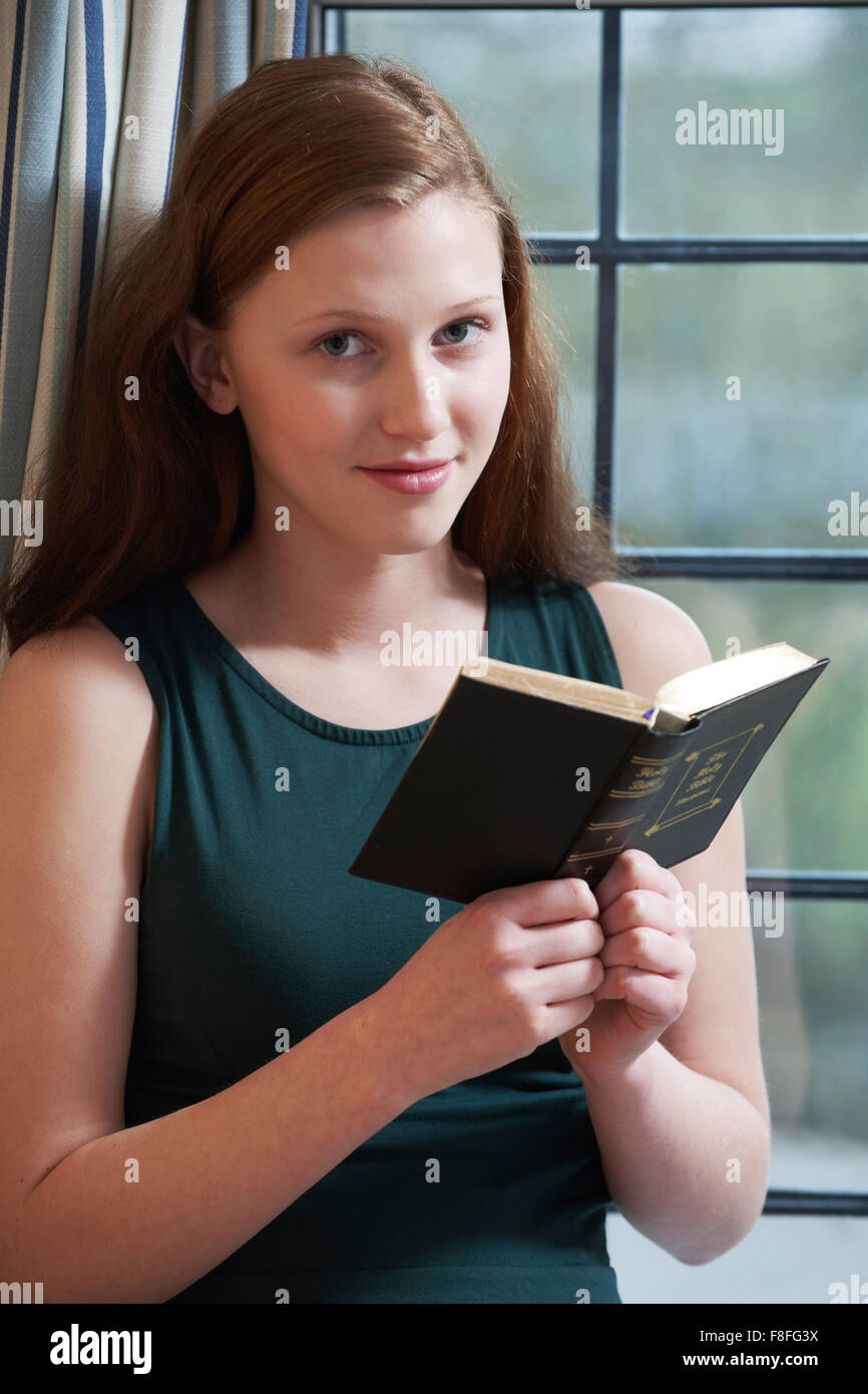 Ragazza adolescente a leggere la Bibbia a casa Foto Stock