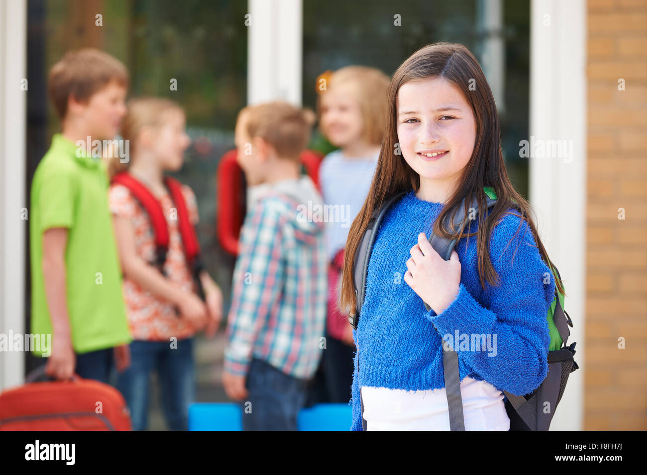 Ragazza in piedi al di fuori della scuola con sacchetto libro Foto Stock