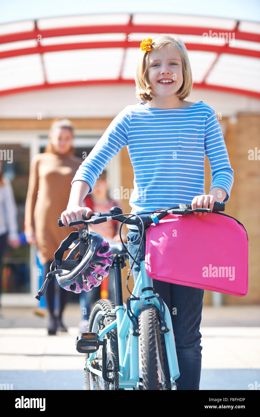 Pupilla d femmina spingendo bici alla fine della giornata di scuola Foto Stock