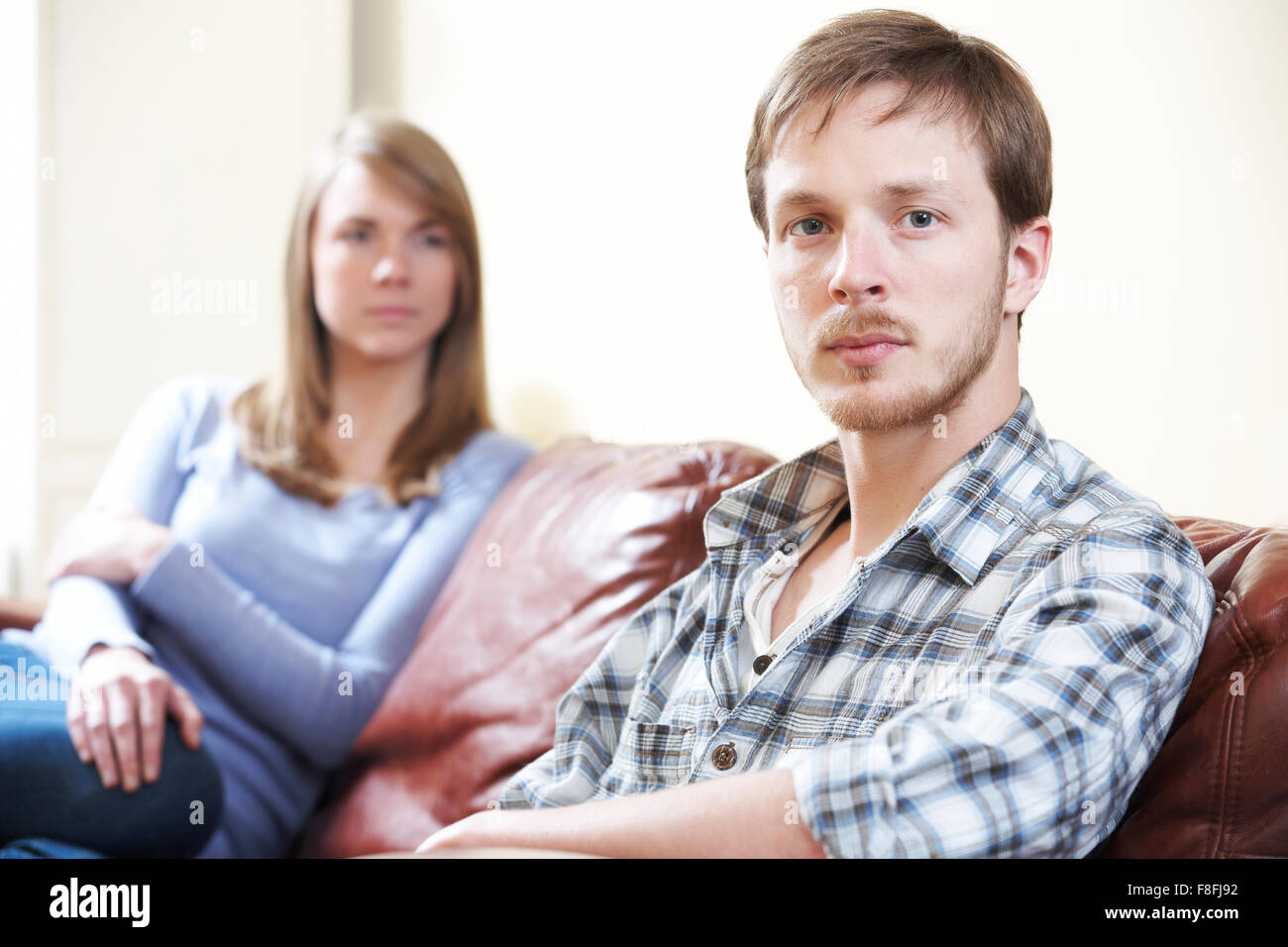 Giovane con difficoltà di relazione seduto sul divano Foto Stock