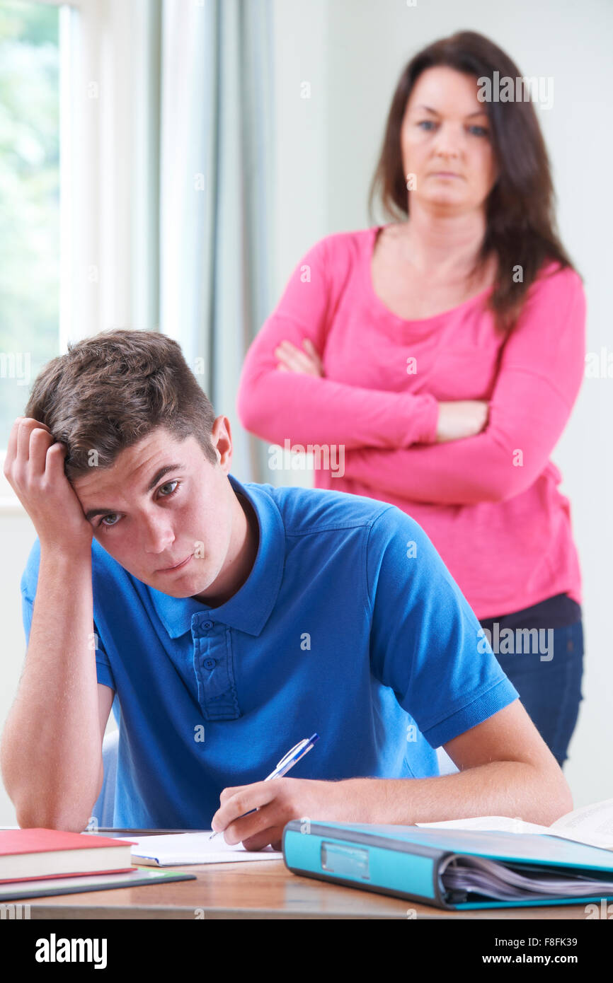 Frustrata madre guardando figlio di fare i compiti di scuola Foto Stock