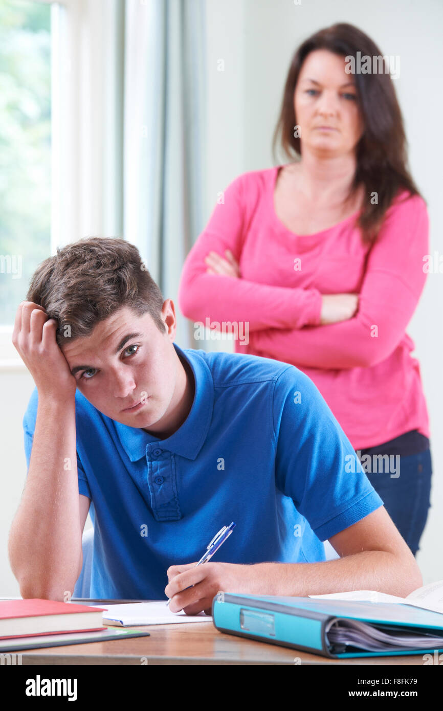 Frustrata madre guardando figlio di fare i compiti di scuola Foto Stock