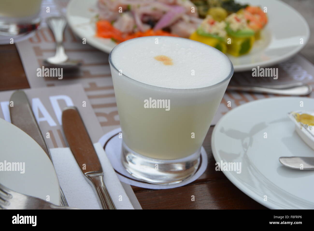 Pisco Sour, bevanda tradizionale a Lima in Perù con ceviche piatto in background Foto Stock