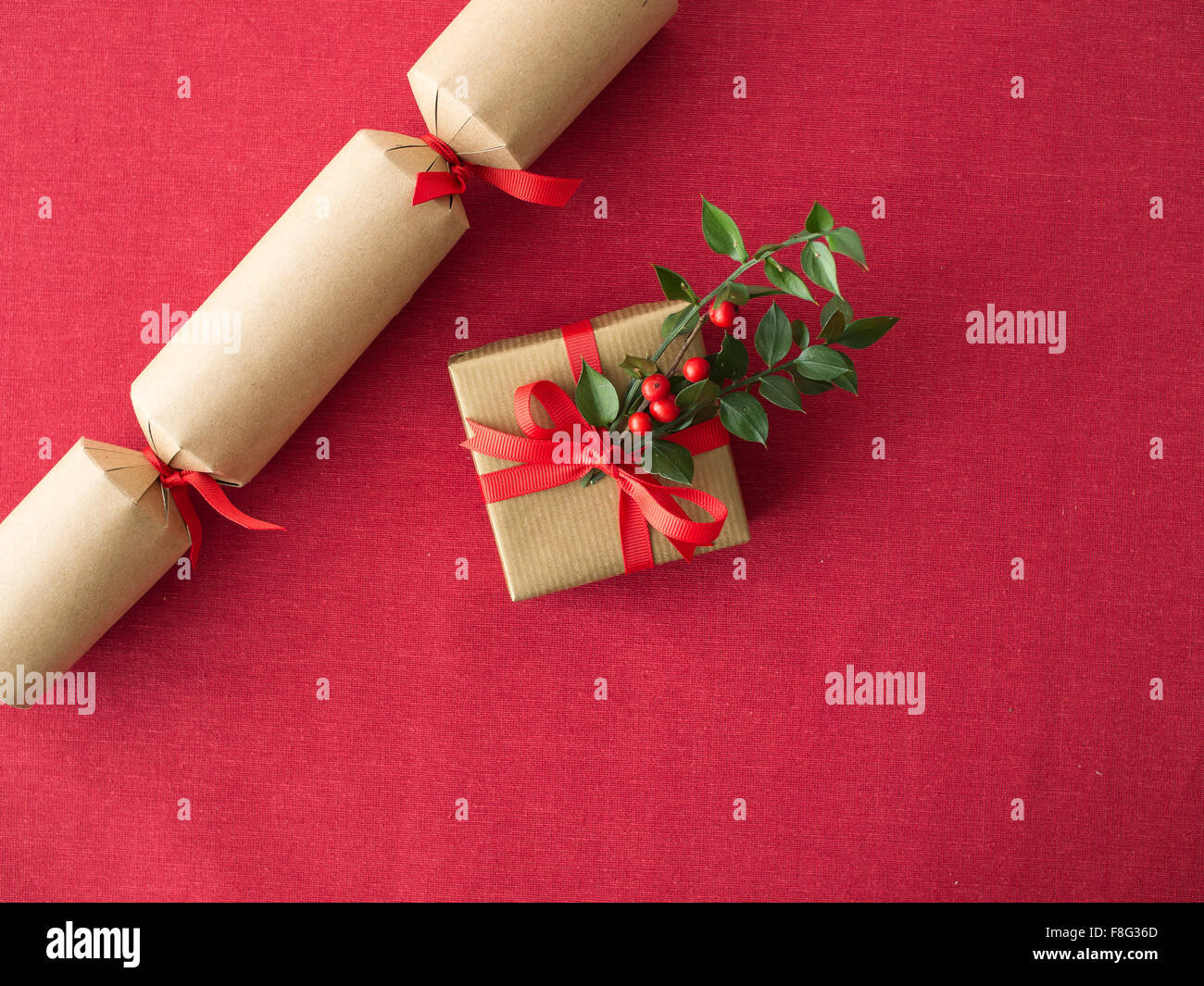 Christmas cracker e presente sulla tovaglia rossa sullo sfondo il concetto di cibo Foto Stock