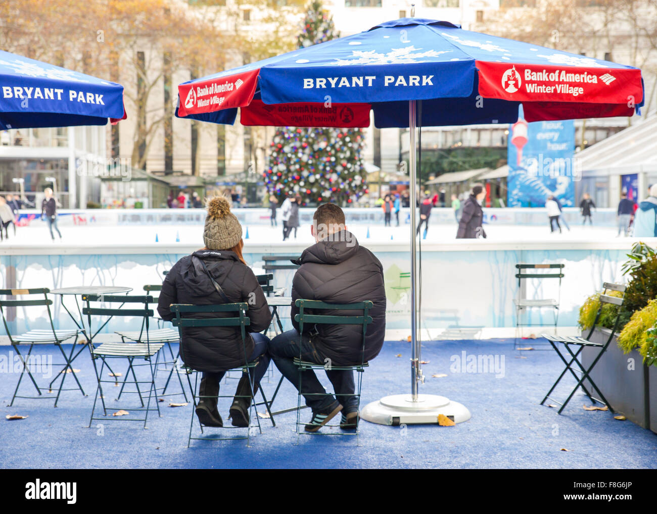 Coppia seduta al Bryant Park Citi Pond in New York City con albero di Natale visibile in background durante le vacanze Foto Stock