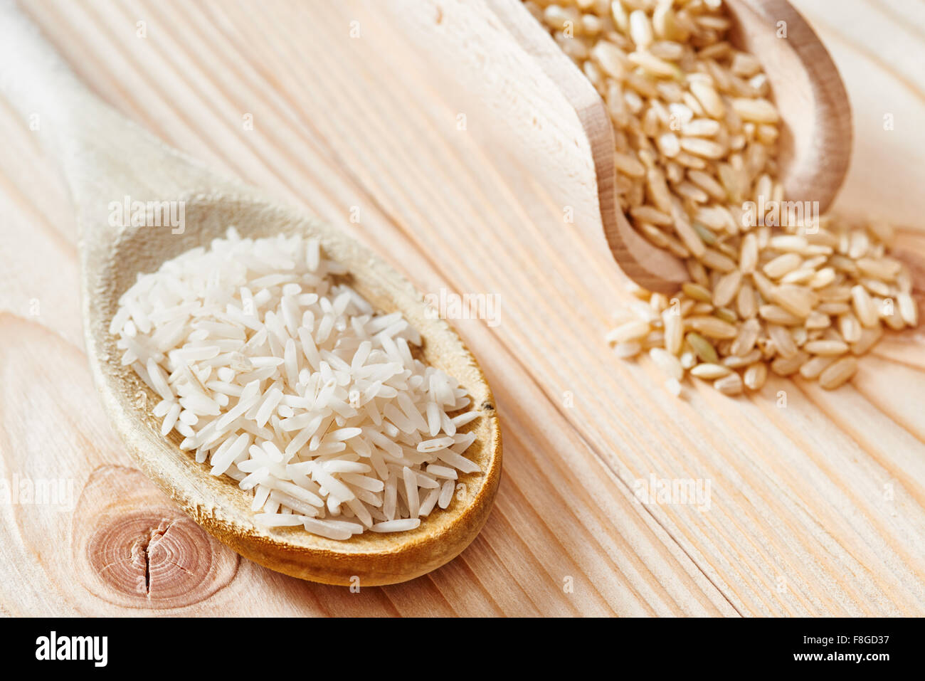 Riso Basmati e riso marrone sul cucchiaio collocato sulla luce tavolo in legno Foto Stock Riso Basmati e riso marrone sul cucchiaio collocato sulla luce tavolo in legno Foto Stock