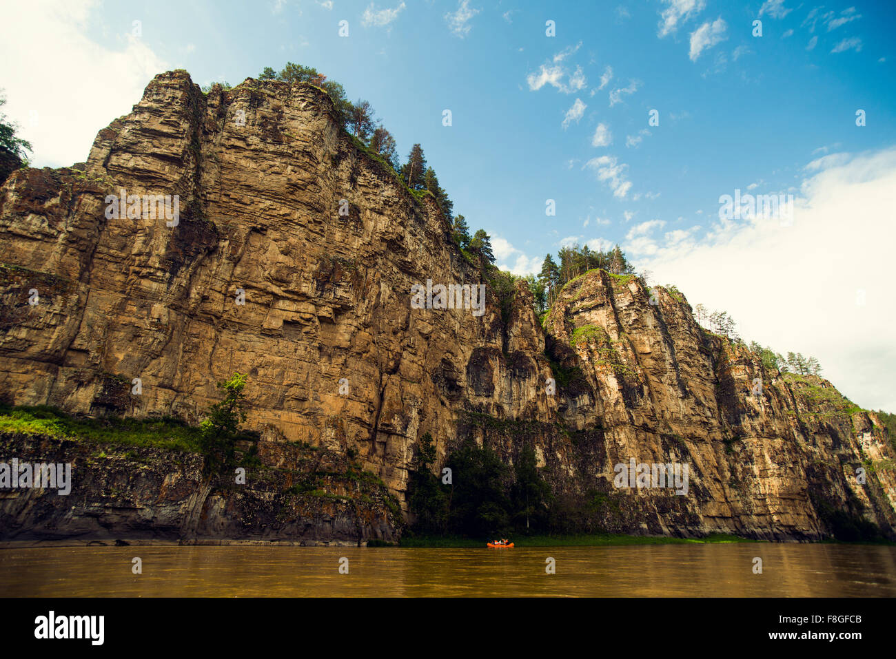 Distante barca sul fiume vicino a cliff Foto Stock